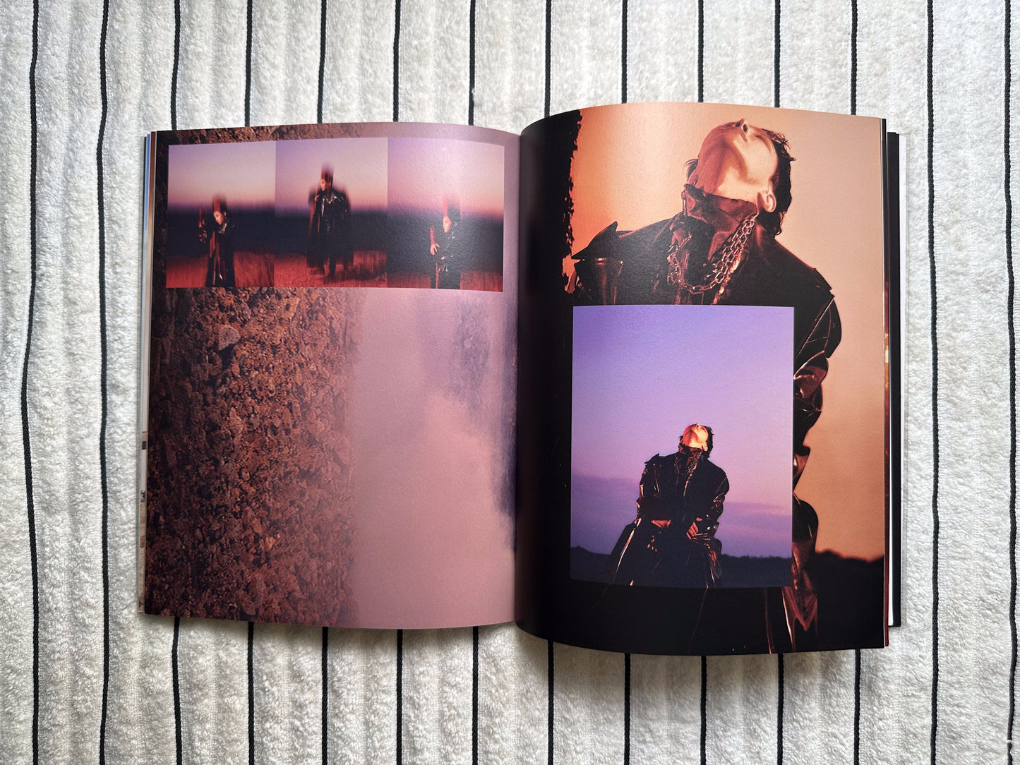 An open photo book or printed album spread laid flat on a light gray ribbed surface. The pages contain multiple artistic photographs with warm and cool tones, including a figure in dark clothing against an orange sky and a purple-toned portrait.