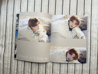 Open book showing a person lying on a bed with a blanket, titled 'Wholly or Whole me'.